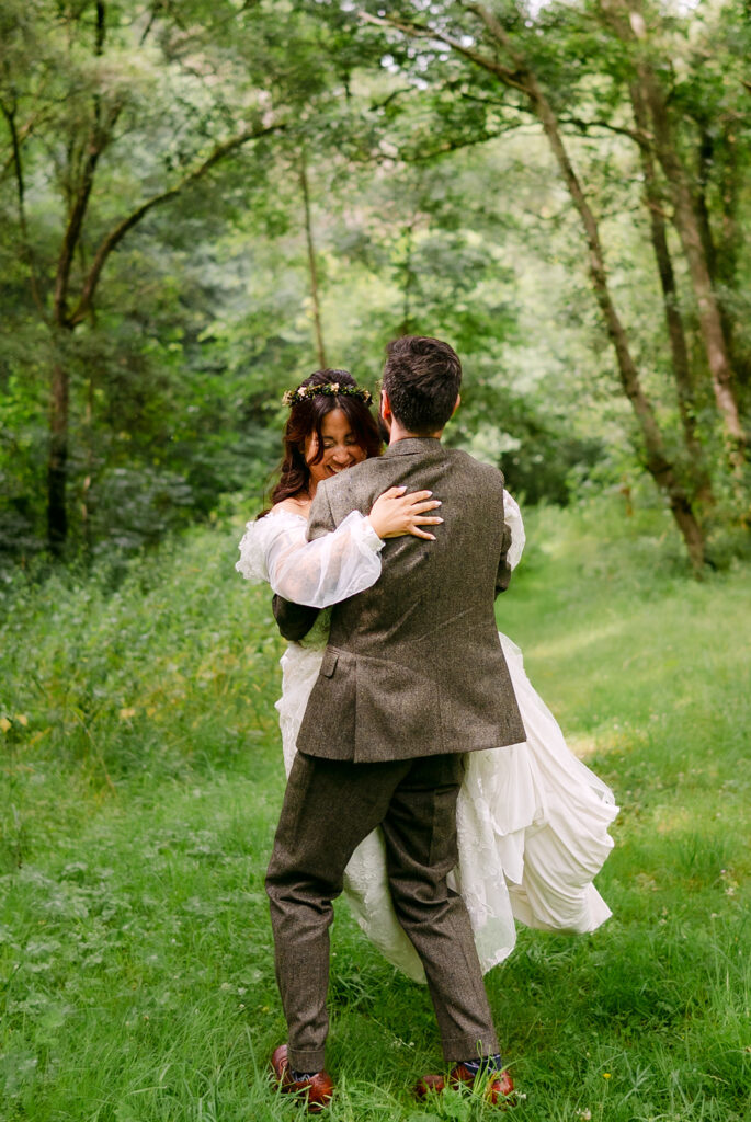 Couple embracing in lush green garden during outdoor wedding.