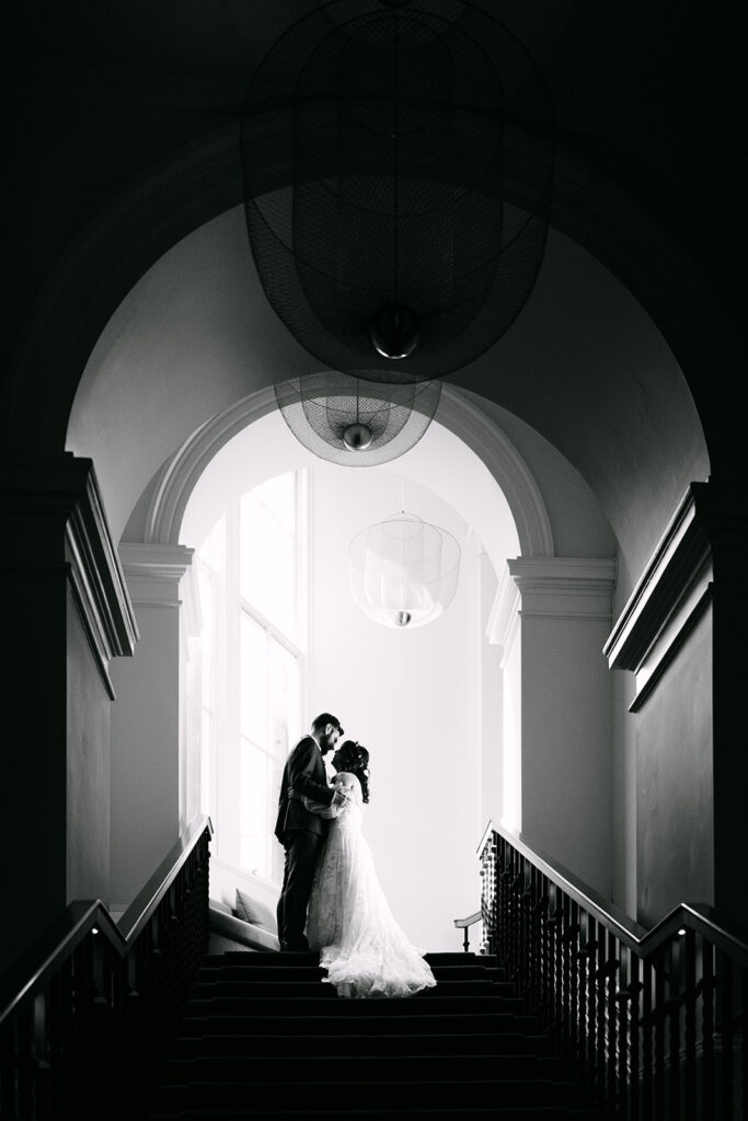 Couple embracing in arched hallway in black and white.