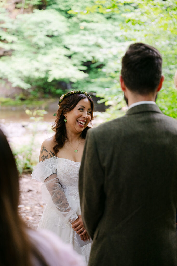 Bride smiling at groom during outdoor ceremony.
