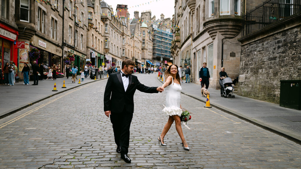 Couple walking hand in hand through Edinburgh street.