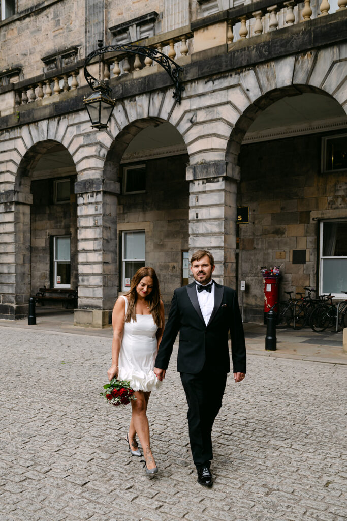 Bride and groom walking together in courtyard after ceremony.
