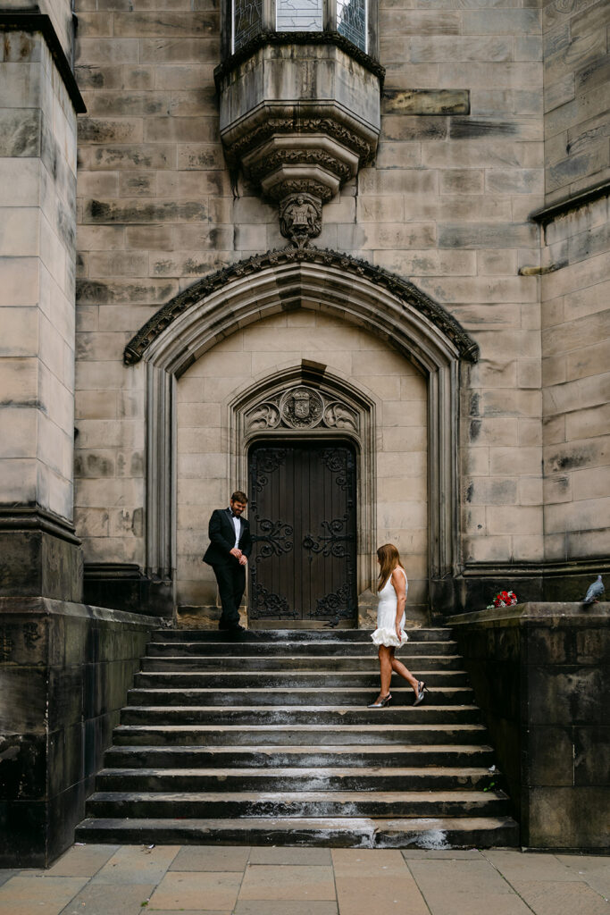 Couple standing on steps outside historic stone building.