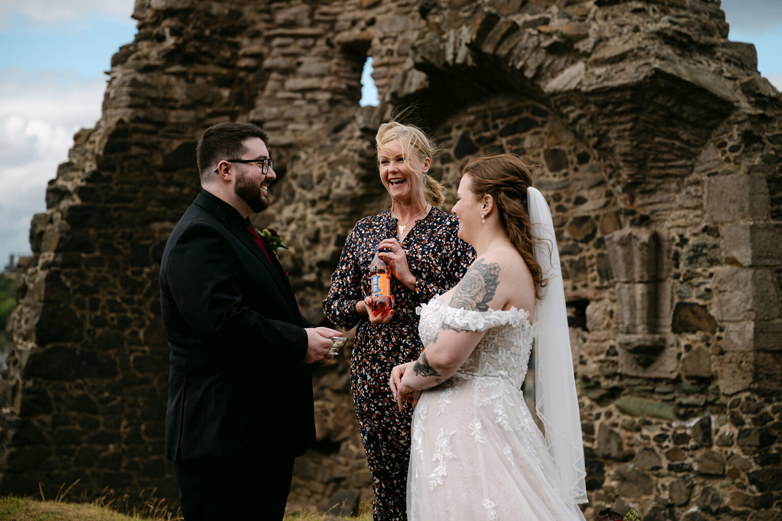 Bride and groom speaking with officiant during outdoor ceremony.
