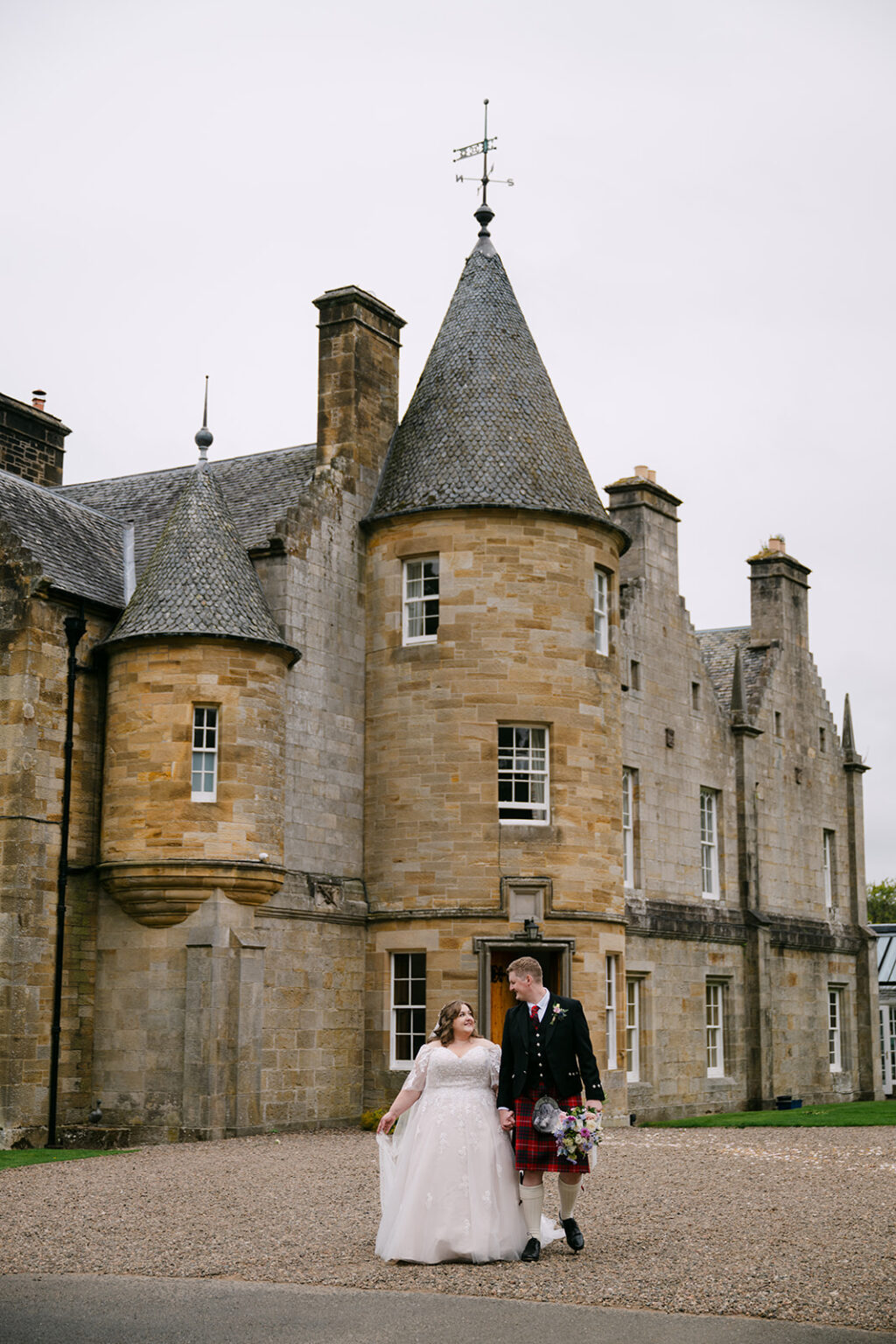 Historic castle exterior with bride and groom nearby.
