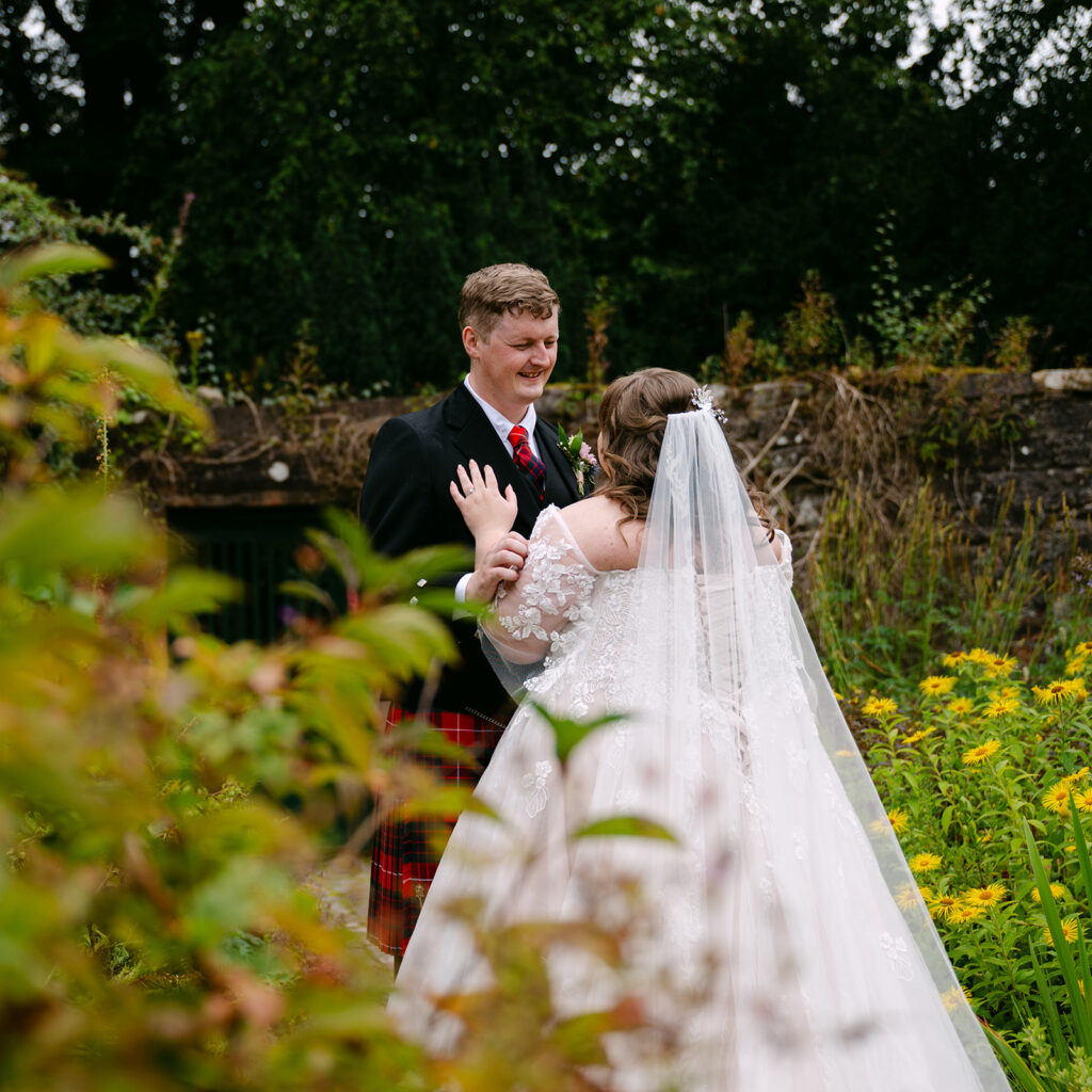 Couple standing together in garden outside stone building.