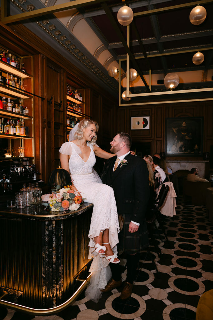 Bride and groom sitting together at bar during relaxed reception moment.