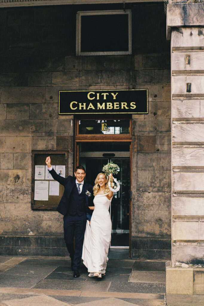 couple emerges from Edinburgh City chambers with their hands thrown up in a cheer after having just been married