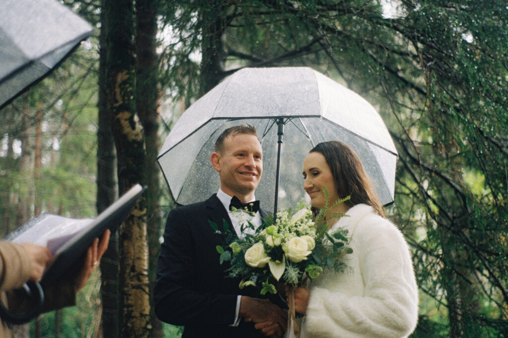 couple huddles under umbrella during rainy glencoe elopement