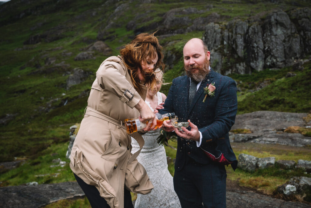 celebrant pours whisky into quaich while whisky blows towards camera in the wind