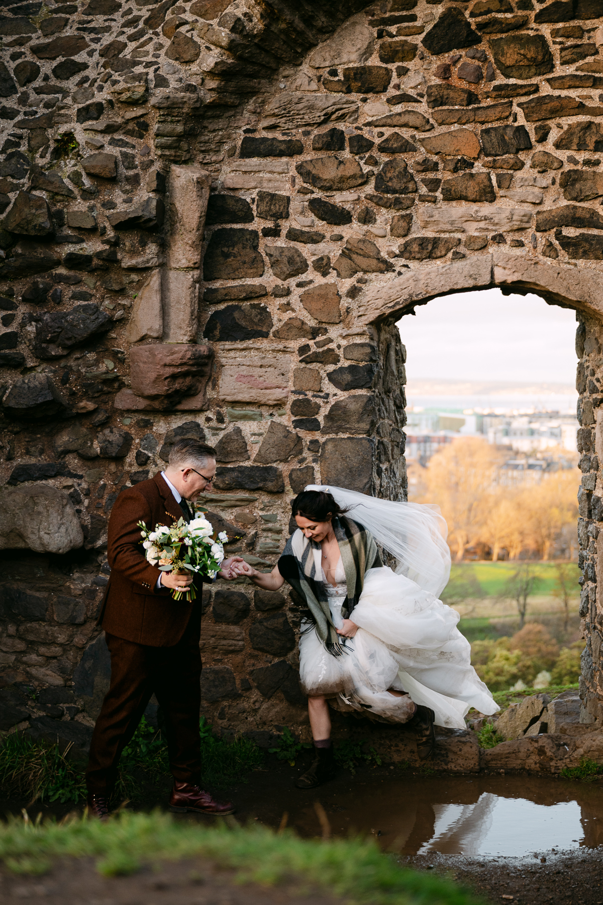 bride hops over a puddle in a wedding dress