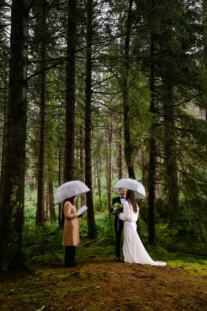 couple elopements in Glencoe's glen Lohan forest under umbrellas on a rainy day