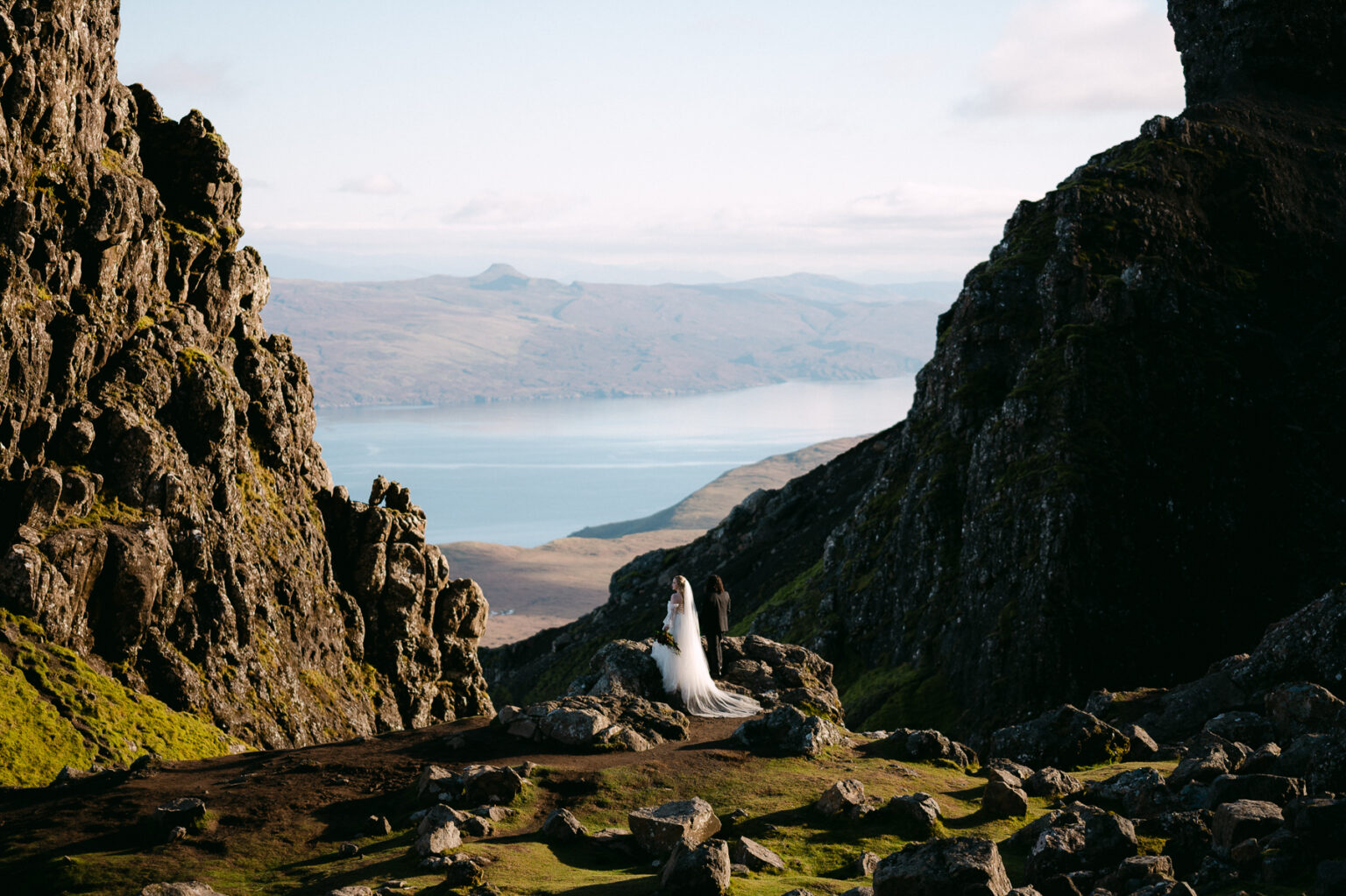 wedding couple stands on old man of storr with ocean in the distance