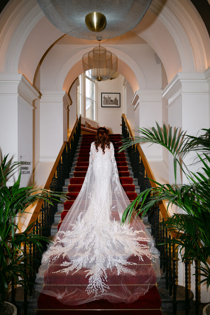 bride in virgin hotels edinburgh showcases wedding cape on stairs