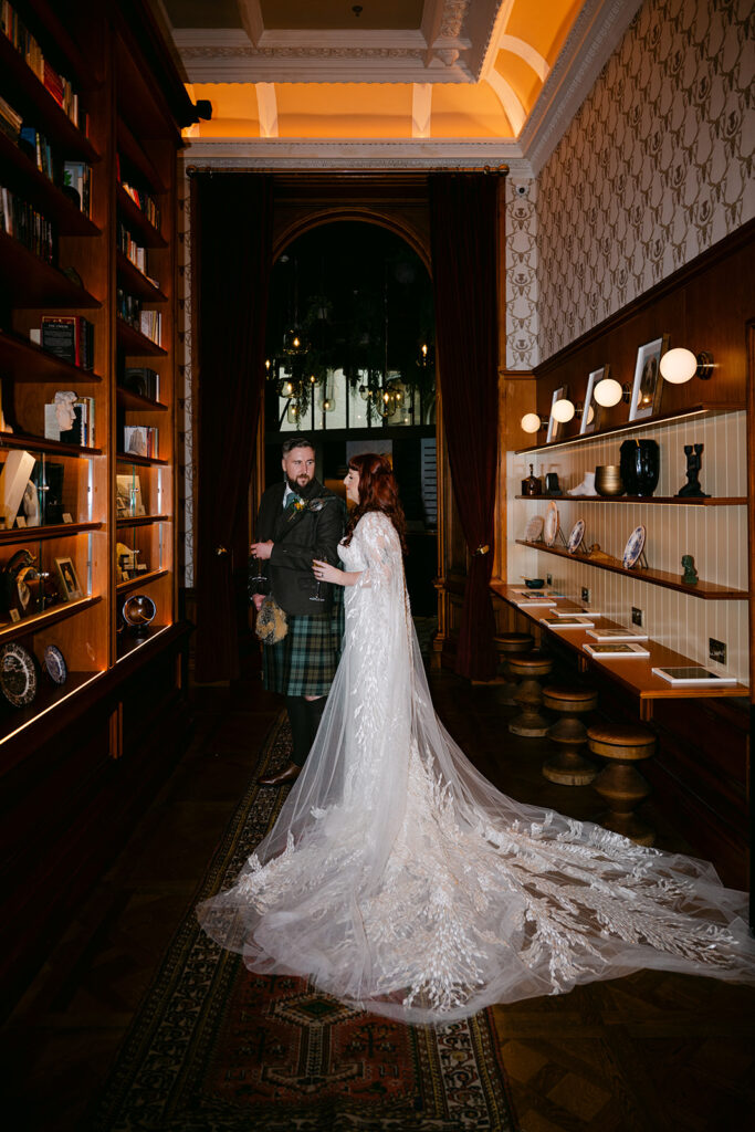 wedding couple stands in library at VIRGIN HOTELS EDINBURGH