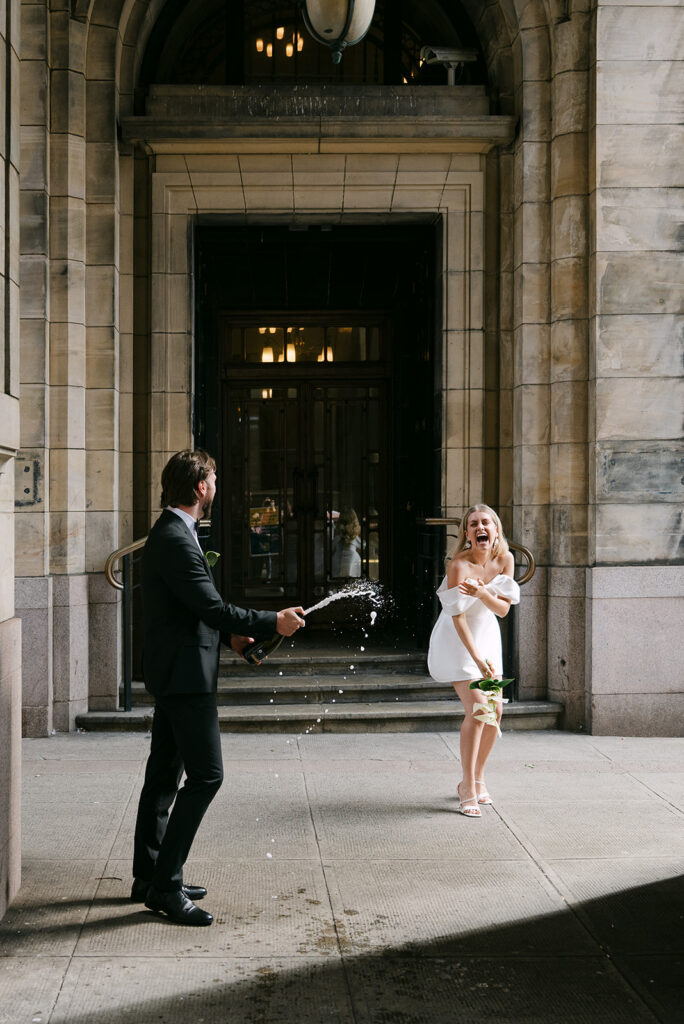 groom sprays bride with a bottle of champagne in glasgow