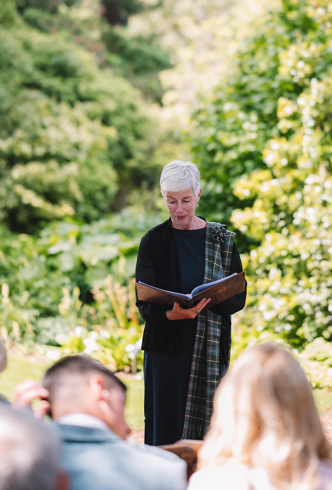 Officiant reading during outdoor wedding ceremony in garden.