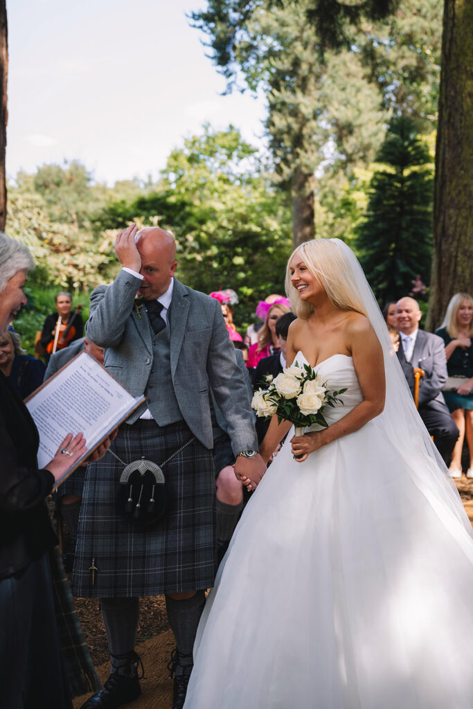 Bride smiling while walking with escort during ceremony.
