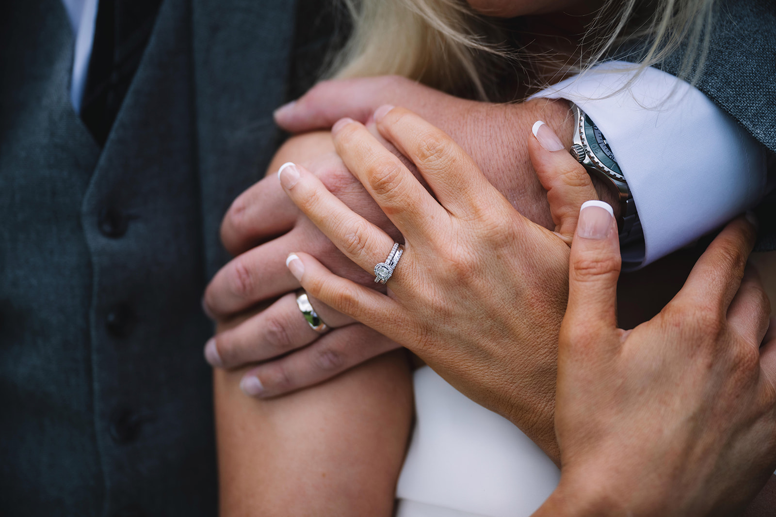 Close-up of bride’s hands showing wedding rings during intimate moment.