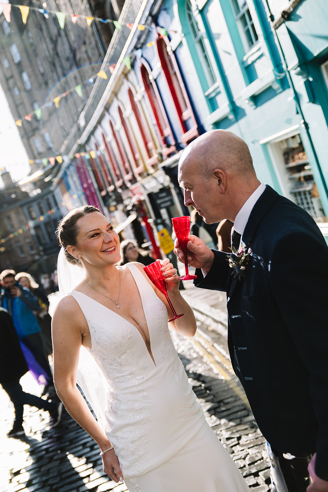 Couple toasting drinks together on colorful city street.