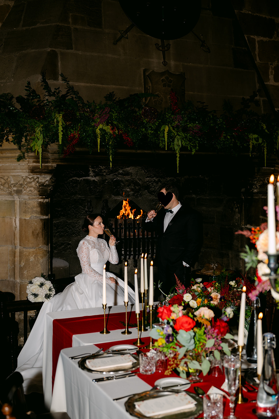 Bride and groom seated at candlelit table during reception dinner.
