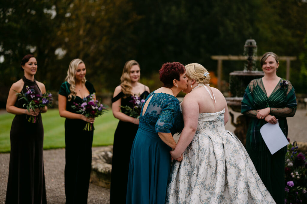 mother of the bride kisses bride on the cheek at the top of the aisle