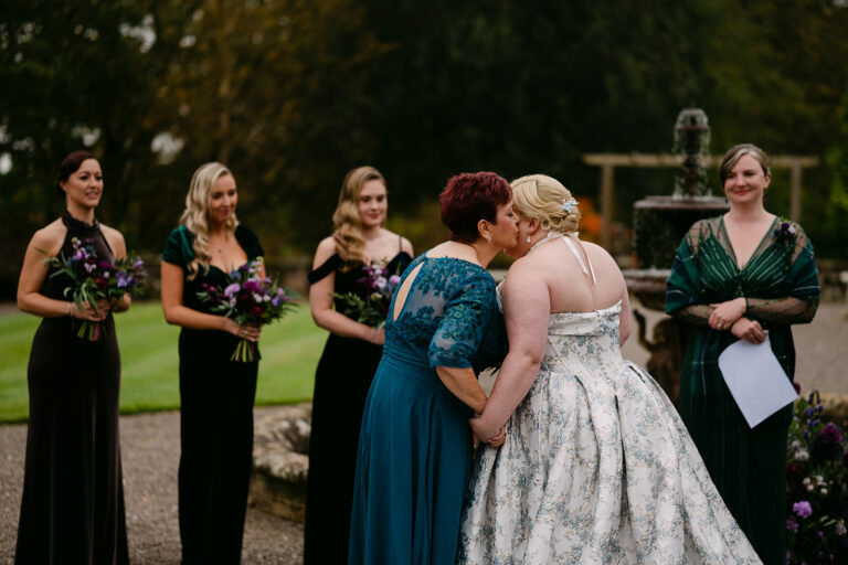 mother of the bride kisses bride on the cheek at the top of the aisle