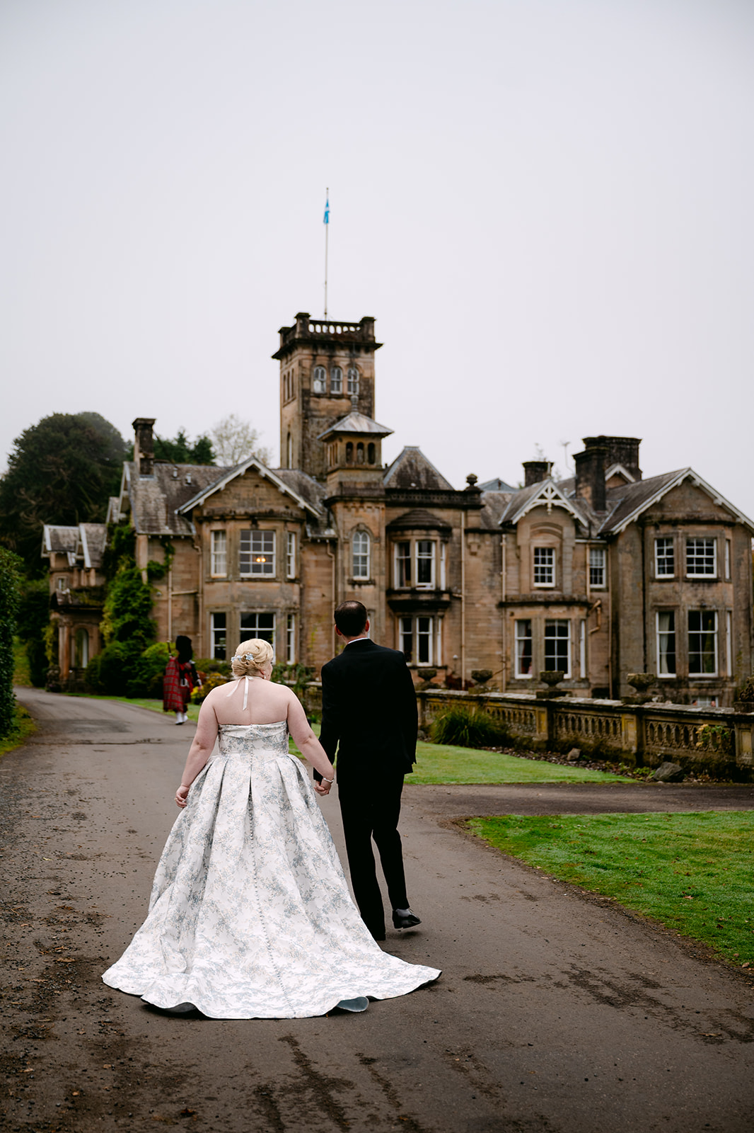 bride and groom walk towards auchen castle led by piper