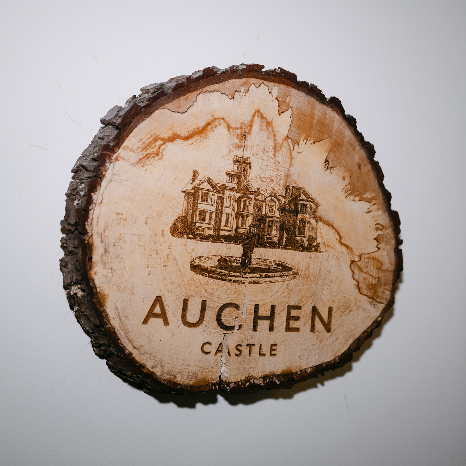 slice of wood with auchen castle stamped on it