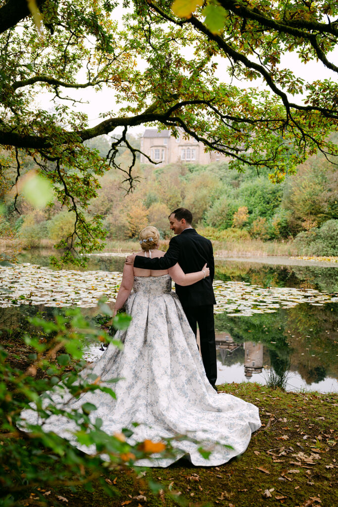 bride and groom look at auchen castle through the mist by the loch