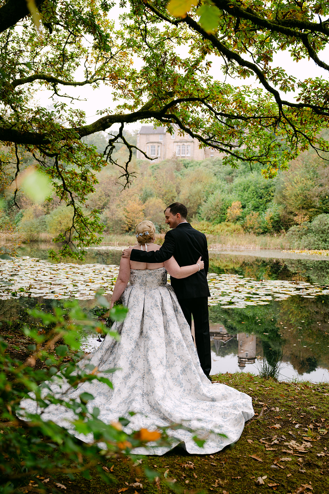 bride and groom look at auchen castle through the mist by the loch