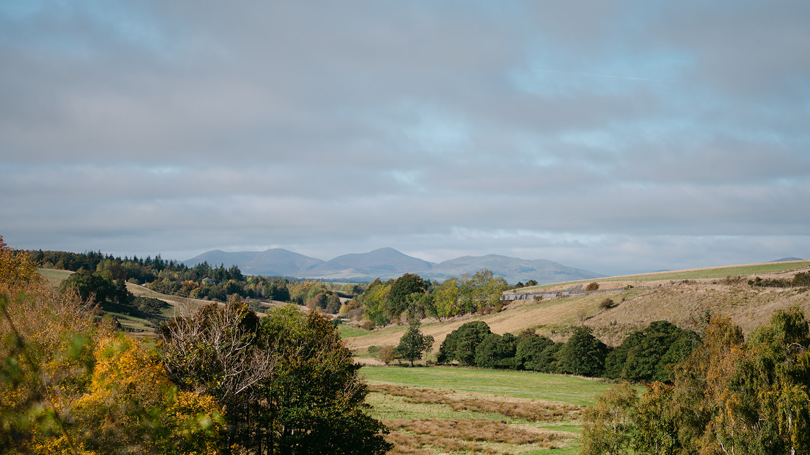 Rolling countryside landscape with hills and distant mountains.
