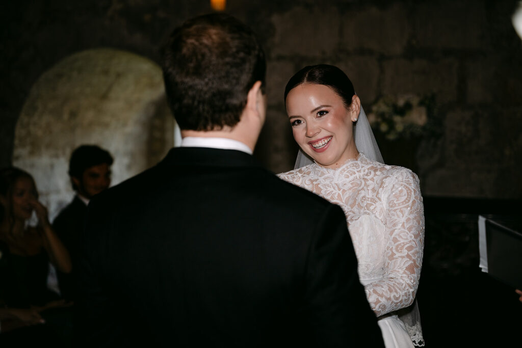 Bride smiling at groom during indoor ceremony moment.