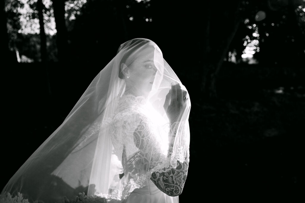 Bride wrapped in veil during intimate bridal moment.
