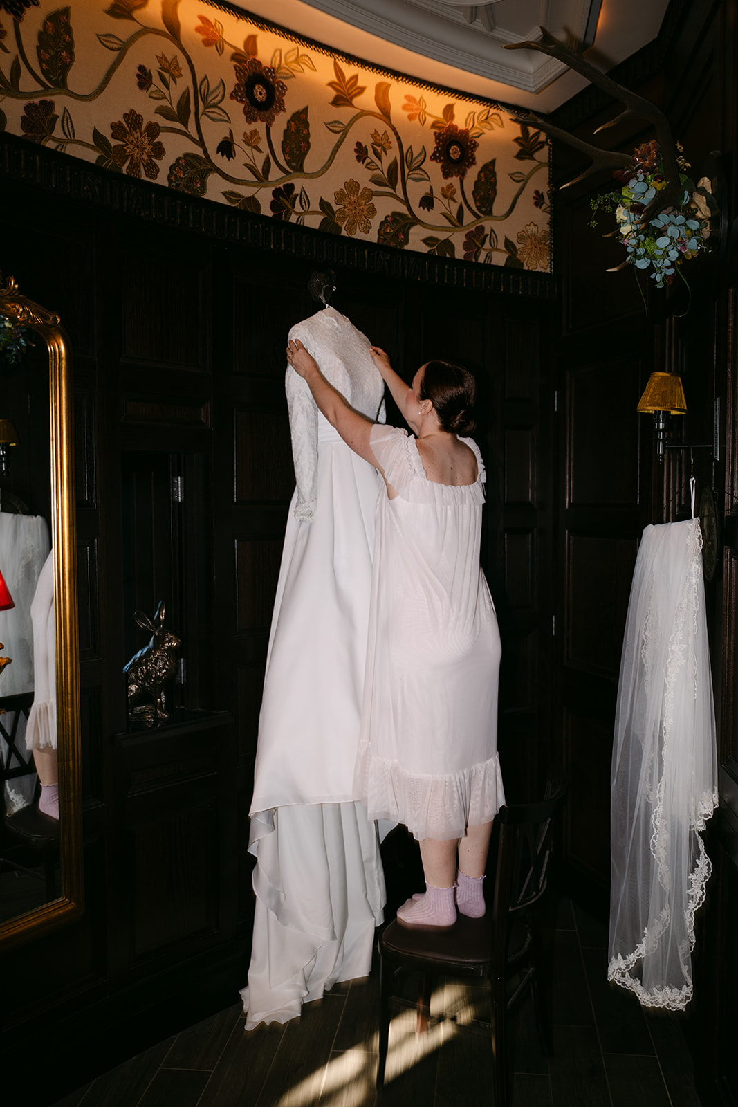 Bride putting on wedding dress in softly lit room.