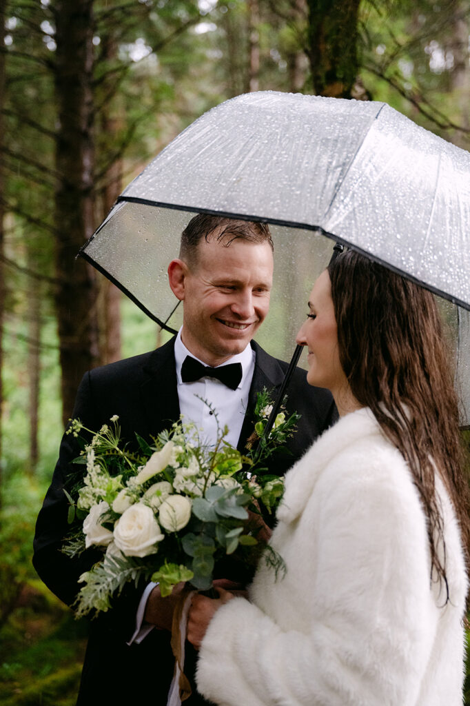 couple stands in glencoe forest during elopement under the rain