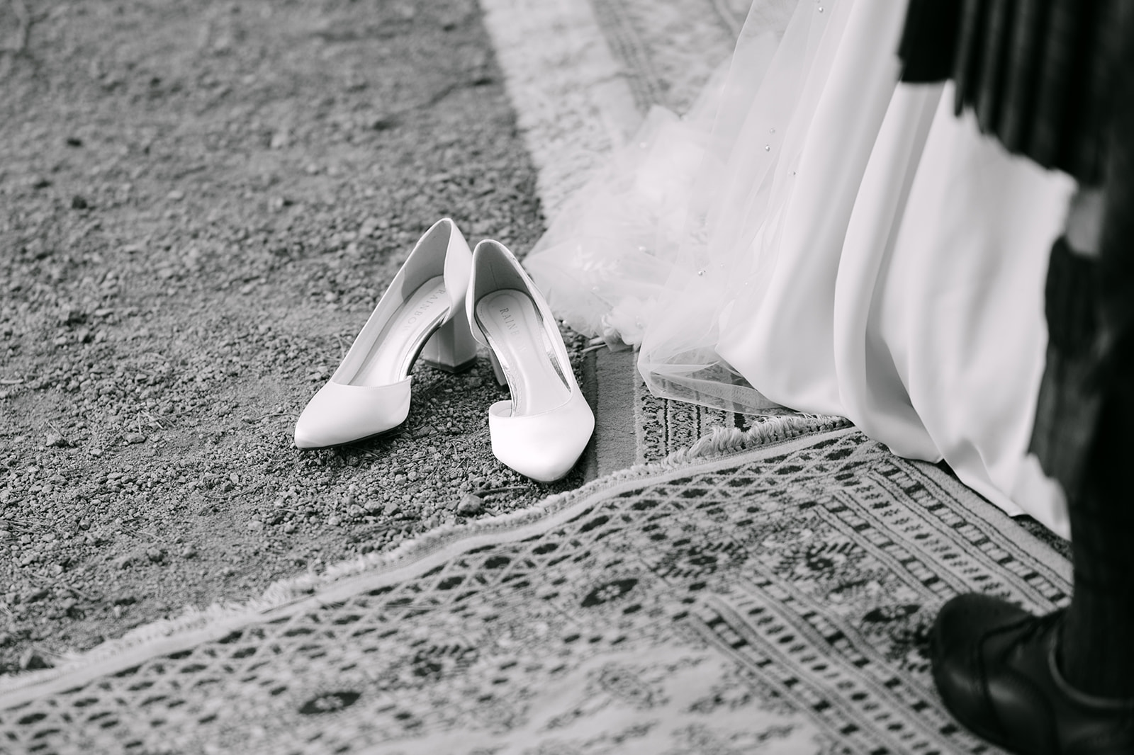 bride's shoes lay to the side during an outdoor ceremony