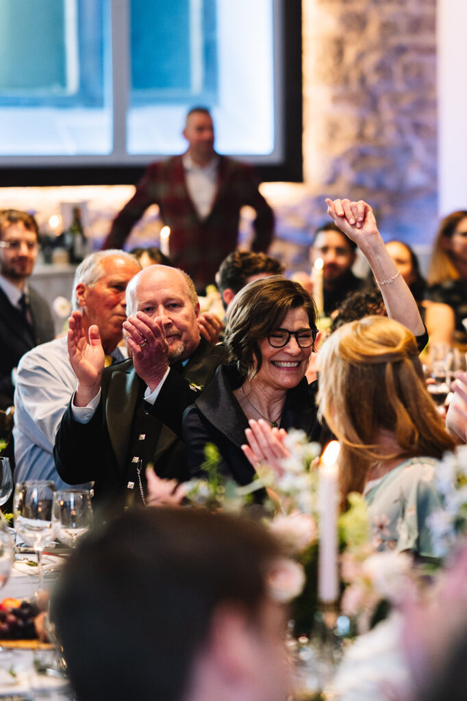 guests clapping and laughing during emotional wedding speech.