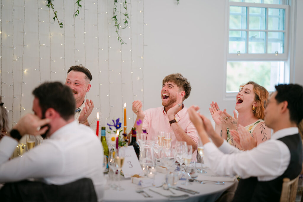 Guests laughing and clapping during reception dinner.