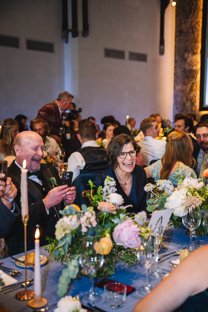 Wedding guests seated at reception table during speech and celebration.