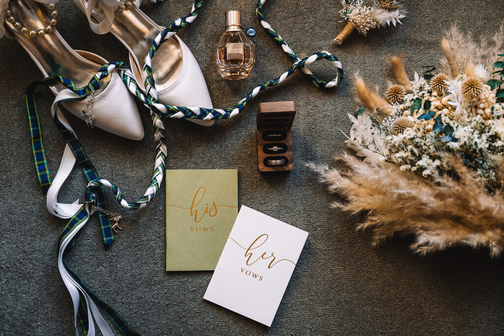 flay lay of wedding vow books, rings, and hand fasting cord