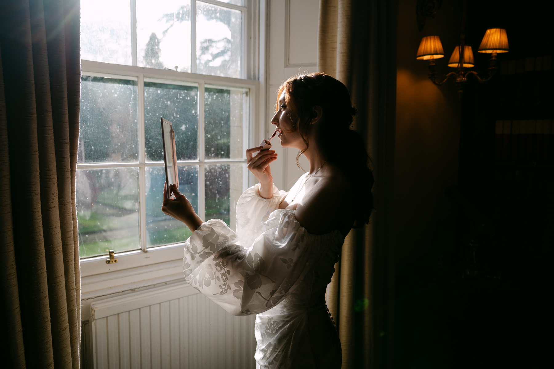 bride applies makeup at kirknewton house stables