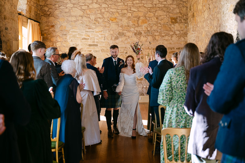 bride and groom walk down the aisle at kirknewton house stables