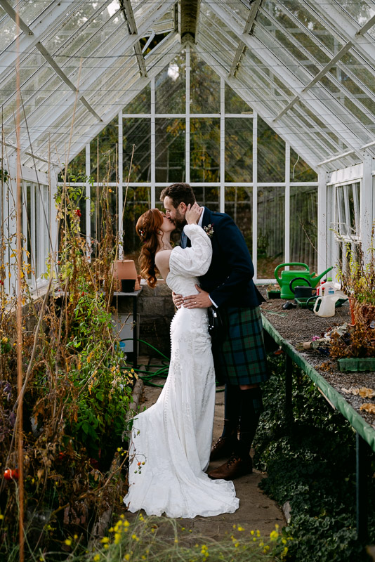 couple kisses in greenhouse at kirknewton house stables