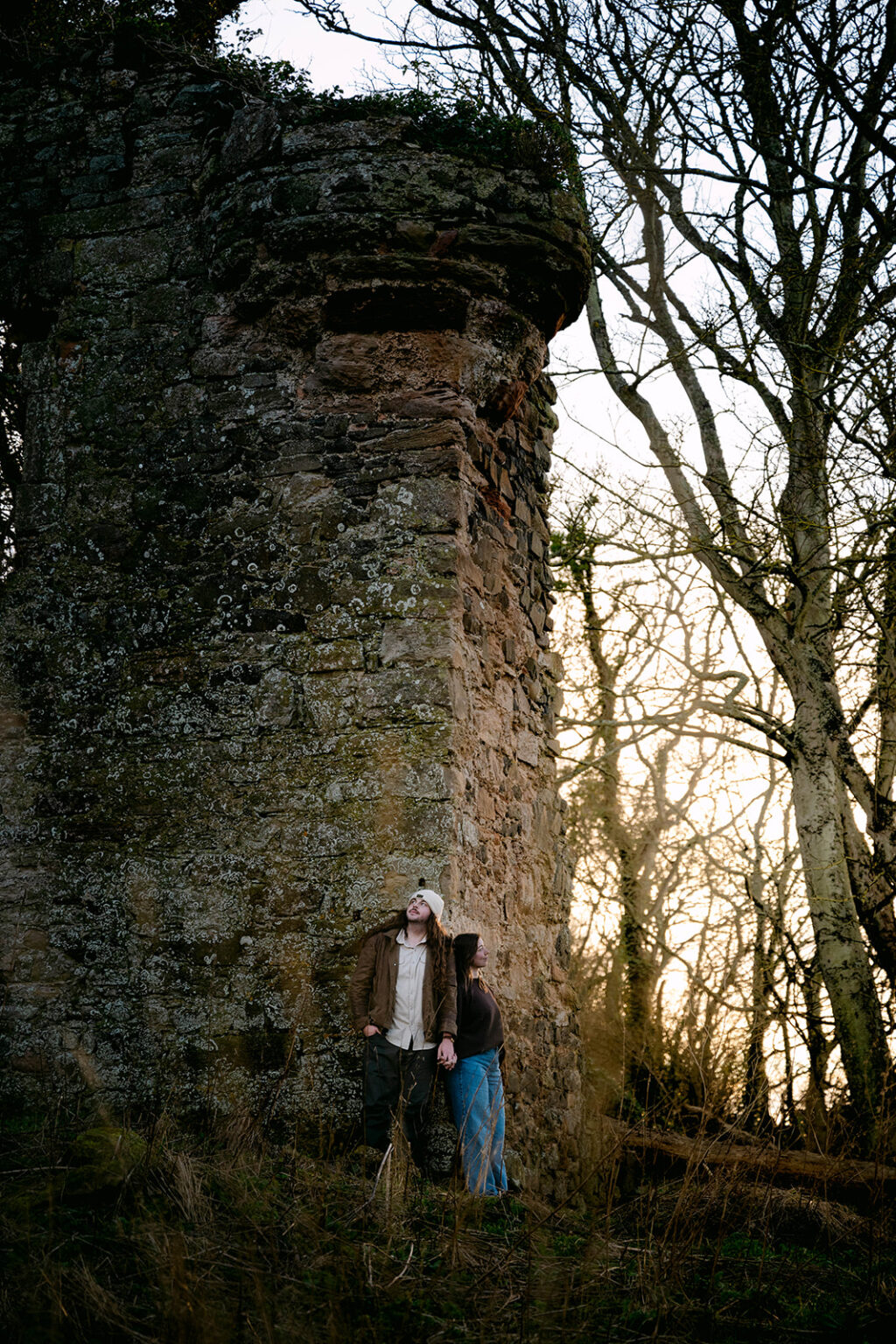 couple stands next to castle ruins in scotland photoshoot