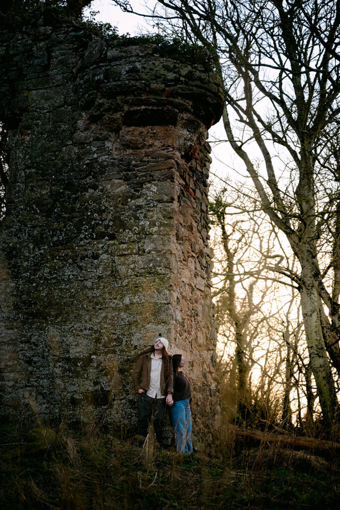 couple stands next to castle ruins in scotland photoshoot