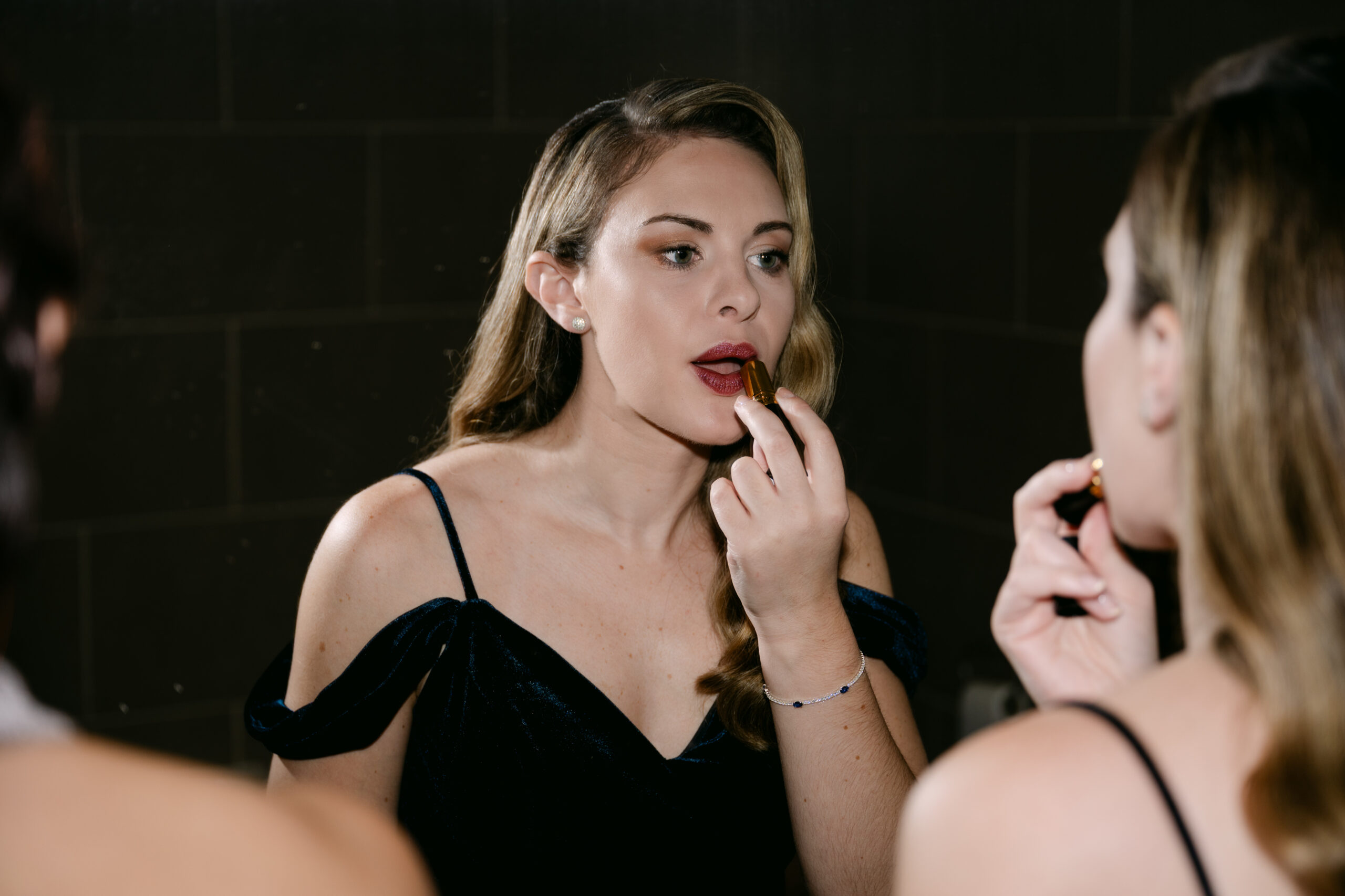 bridesmaid applying puple lipstick ahead of a wedding ceremony at auchen castle